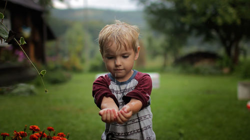 Cute little boy gathering a rain water into his hands, water economy concept