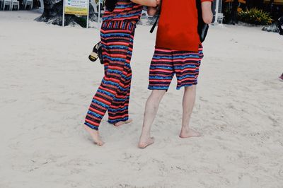 Low section of couple walking on sandy beach