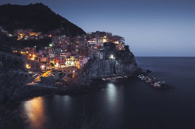 Buildings by sea in vernazza at night