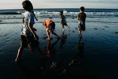 Rear view of people playing on beach