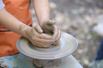 Midsection of man making clay pot on spinning wheel