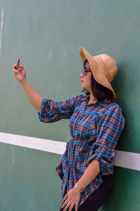 Midsection of woman holding hat while standing against water