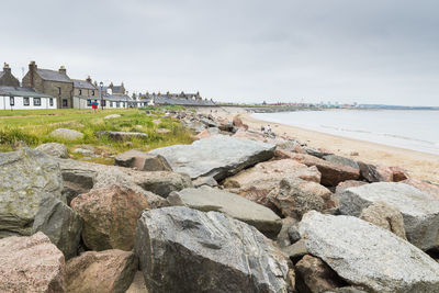 Boulders in the foreground with beach and houses in the background, aberdeen, scotland