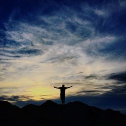 Low angle view of silhouette people standing on mountain against sky