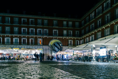 People walking on street by buildings at night