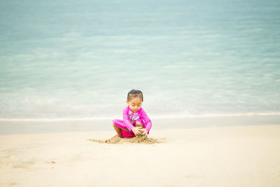 Cute girl playing with sand at beach