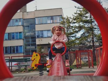 Toddler girl at the playground riding seesaw.