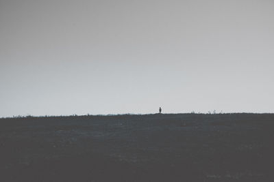 Silhouette person on field against clear sky