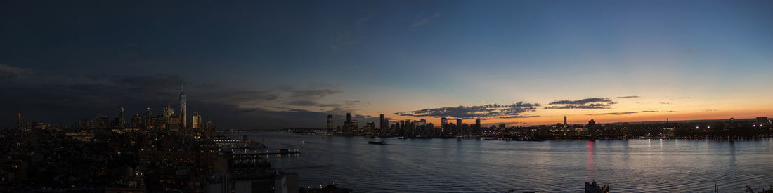 Panoramic view of sea and buildings against sky during sunset