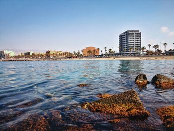 Sea by buildings against clear sky