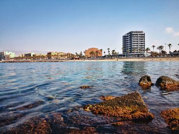 Sea by buildings against clear sky