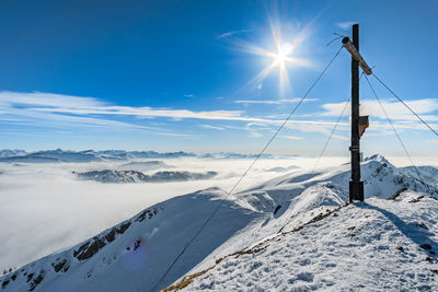 Scenic view of snow covered mountains against bright sun