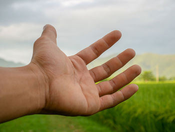 Close-up of person hand against sky