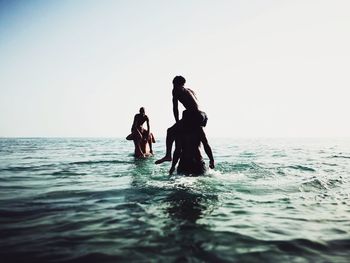 Silhouette people on sea against clear sky