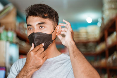 Close-up portrait of young man holding covering face