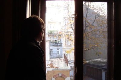 Young man looking through window