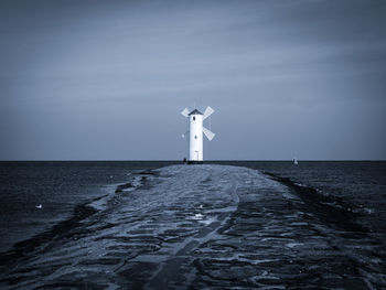 Lighthouse by sea against sky