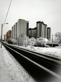 Railroad tracks in city against clear sky during winter