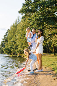 A happy family with two children have fun outdoors in summer by the lake. my daughter launches