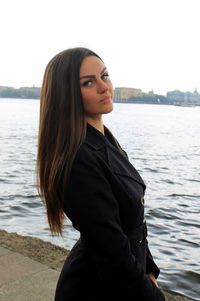 Portrait of beautiful young woman standing at shore