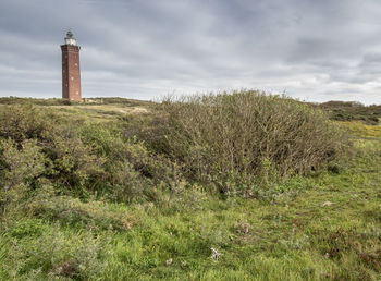 Lighthouse on field against sky