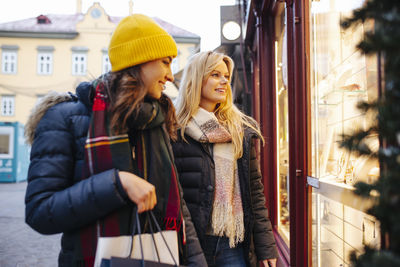 Friends looking through window of store at christmas market