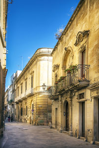 Street amidst buildings against clear blue sky