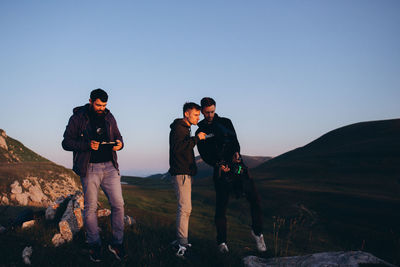 People standing on mountain against clear sky