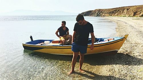 Men in boat on beach against sky