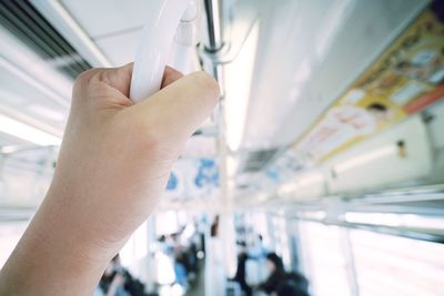 Cropped hand of person holding handle in bus