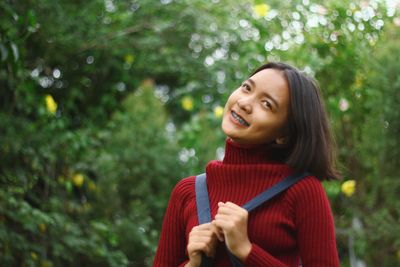 Smiling teenage girl against trees in forest