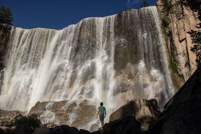 Rear view of man standing against waterfall