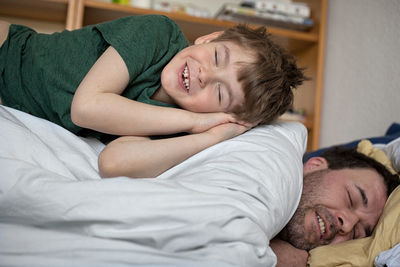 Portrait of happy father and son sleeping on bed at home