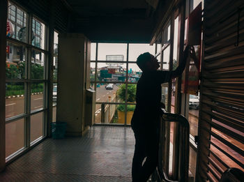 Side view of man standing by window in building