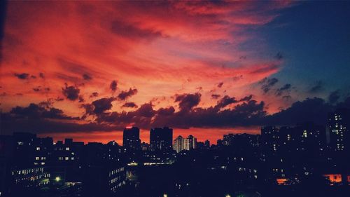 Cityscape against cloudy sky at sunset