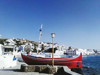 Boats moored at harbor against clear blue sky