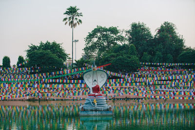 Fountain by lake against clear sky