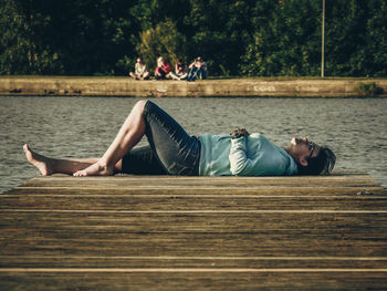 Woman lying down on pier over lake