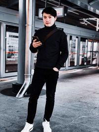 Portrait of young man standing on footpath