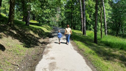 Rear view of woman with son walking on road