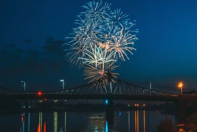 Firework display over river against sky at night