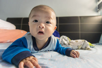 Portrait of cute baby lying on bed at home