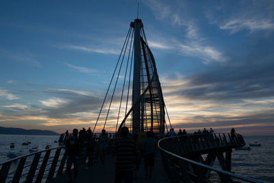 People on sailboat by sea against sky during sunset