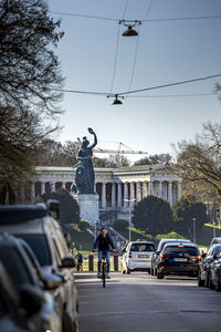 Statue on street in city against sky