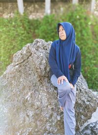 A girl is leaning against a rock