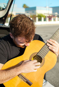 Midsection of man playing guitar