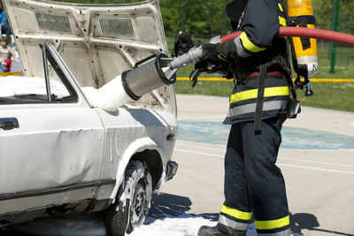 Low section of firefighter spraying water on car