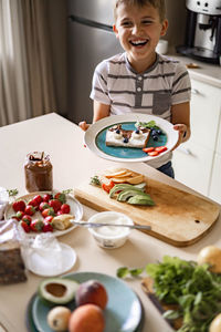 Portrait of smiling boy eating breakfast at home