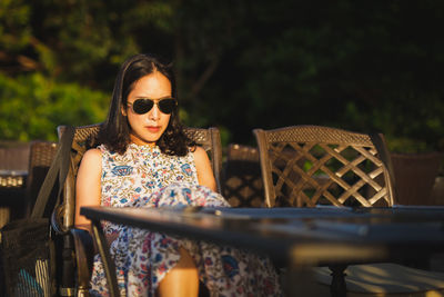 Portrait of woman wearing sunglasses while sitting on table