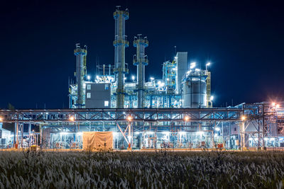 Illuminated factory against sky at night